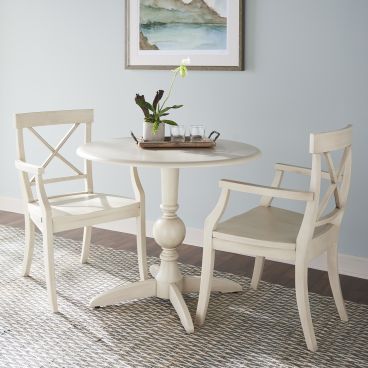 Classic round dining table with two matching wooden chairs, featuring an X-back design and a pedestal base