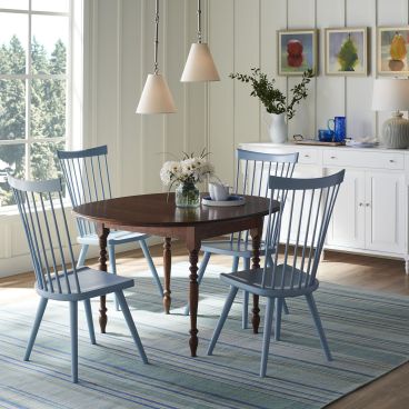 A handcrafted solid wood dining table with turned legs, paired with spindle-back chairs, designed for timeless style and durability.