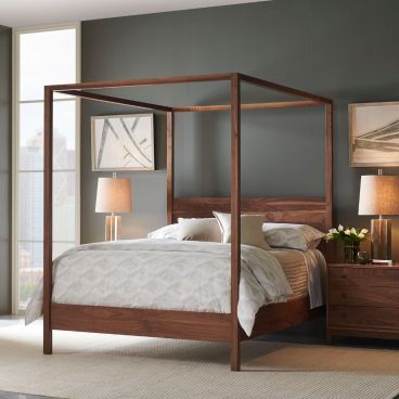 Wooden platform bed with clean lines and a canopy frame in a modern bedroom, paired with matching nightstands and warm lighting.
