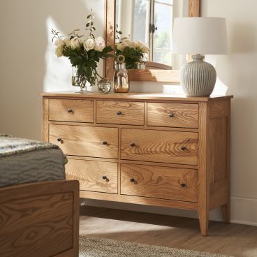 Solid wood Vineyard 54" Dresser with a beautifully crafted mirror, adorned with a vase of roses and a table lamp.