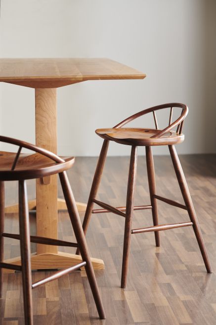 Modern cherry pub table with a trestle base and black bar stools, designed for dining or entertaining in contemporary interiors.