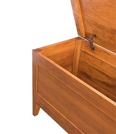 A real wood storage chest made from sustainably sourced Appalachian cherry hardwood, featuring a paneled front and durable metal hinges for smooth operation.