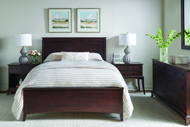 Real wood bed in a bedroom with wooden nightstands and two lamps.