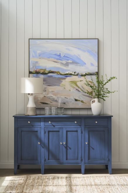 Handcrafted blue wooden buffet with a modern lamp and abstract artwork on display