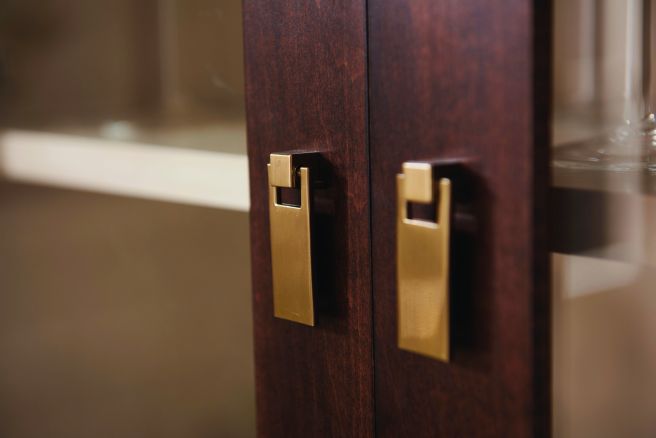 Detailed view of the brass door handles on a handcrafted glass cabinet.