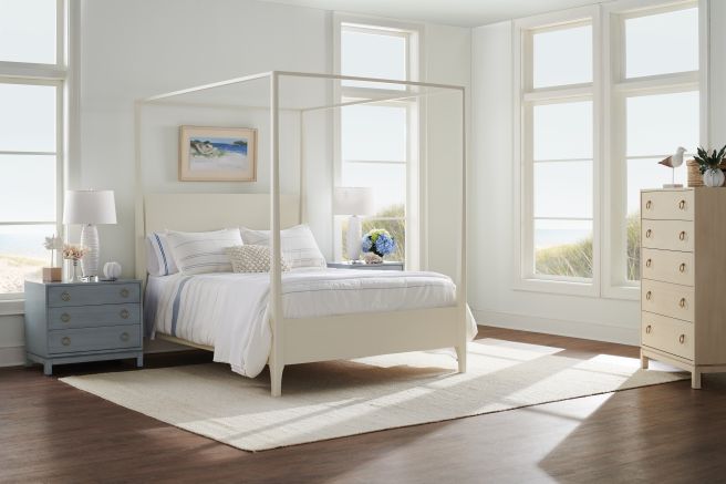 Solid wood canopy bed paired with matching furniture in a bright coastal bedroom setting.