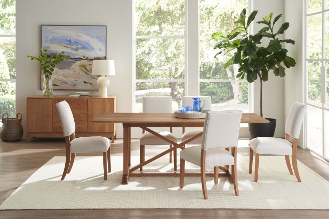 Inviting dining space with a solid wood table and chairs, complemented by a wooden sideboard and modern decor, all illuminated by natural light.