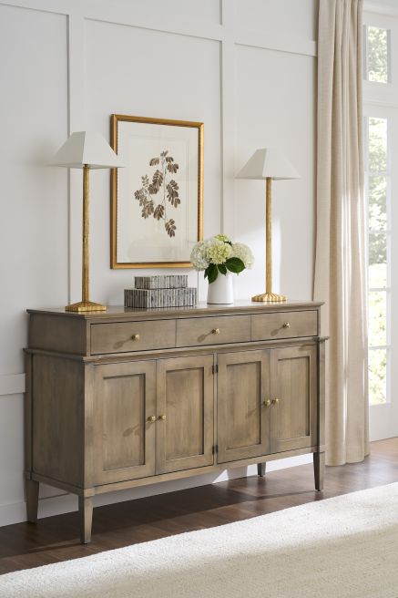 Solid wood buffet with clean lines, complemented by golden lamps and botanical wall art.