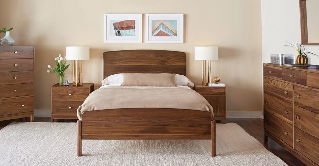 A modern bedroom featuring a handcrafted solid wood bed, matching nightstands, and dressers, creating a warm and inviting space.