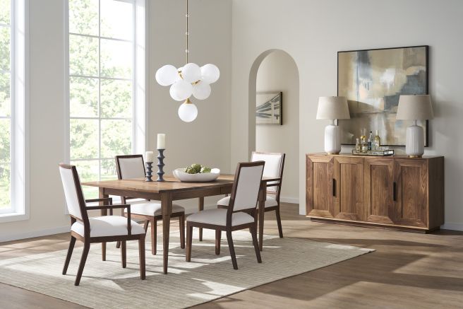 Walnut dining room setup with sleek armchairs and a modern chandelier, featuring natural light through large windows.