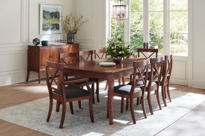 Beautifully arranged dining room with a rich wooden table and chairs, accented by a wooden sideboard and greenery, creating a warm and inviting atmosphere.