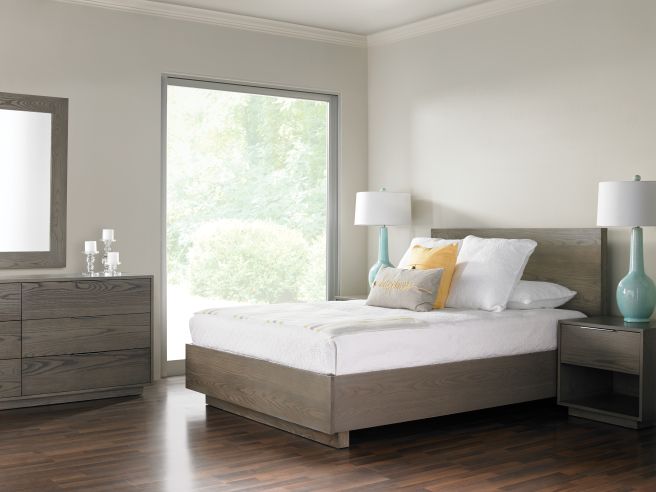 bedroom featuring a minimalist light wood bed, contemporary furniture, and natural light streaming through large windows.