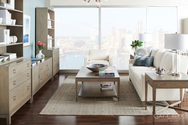 Modern wood furniture set with coffee table, side table, and bookshelves in a bright living space.