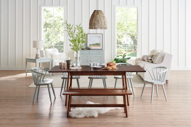 Warm and inviting dining space featuring a rectangular wooden table paired with matching benches and modern chairs, styled with natural light and cozy accents.
